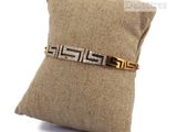 an image of a gold and diamond bracelet sitting on top of a pillow