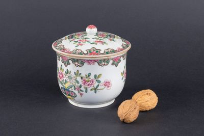 un petit bol avec un couvercle et une noix posés sur une table