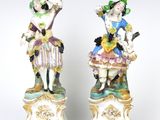 une paire de figurines en porcelaine représentant une femme et un homme, posées sur des socles