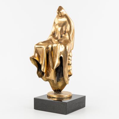 une statue en or représentant une femme assise sur un bloc de marbre