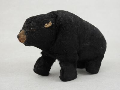 a small black bear that is standing on a white surface