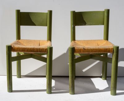 two green chairs sitting next to each other on a white surface
