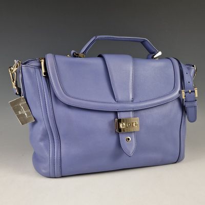 purple handbag with a lock on the front of it on a grey background