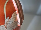 an orange vase with a flower on it on a table