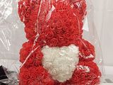 a red teddy bear with a white heart in a plastic bag