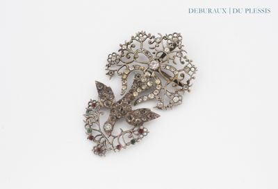 a silver brooch with a bird and flowers on it