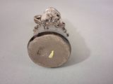 a small silver object with a gold leaf on top of it