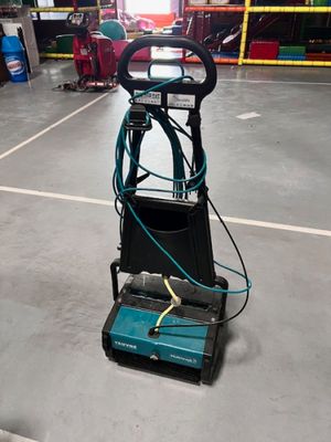 une autolaveuse électrique dans un entrepôt, équipée d'un tuyau