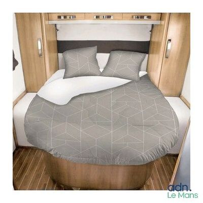 a bed with a grey comforter and pillows in a small room
