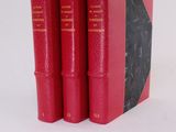 three red books sitting on top of each other on a white surface
