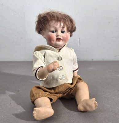 une petite poupée assise par terre, vêtue d'une veste
