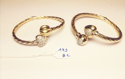 two gold rings with diamonds on them and a price tag on a table