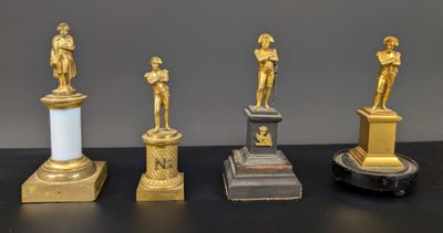 quatre statues d'hommes debout sur des socles posés sur une table