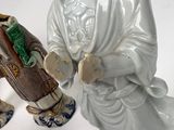 two figurines of a man and a woman sitting on a stool