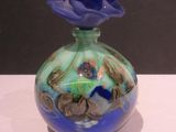 un vase en verre surmonté d'une fleur bleue