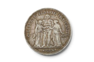une vieille pièce d'argent posée sur une surface blanche, sur laquelle figure l'image d'un groupe de personnes
