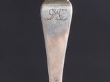 a close up of a silver spoon with a monogram on it