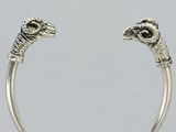 a close up of a silver ring with two rams on it