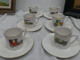 five cups and saucers on a table with a picture in the background
