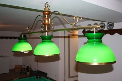 three green lamps hanging from the ceiling above a pool table