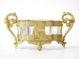 a gold vase with a glass in it on a white surface