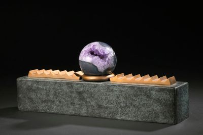 sculpture of a marble ball on a stone block with a black background