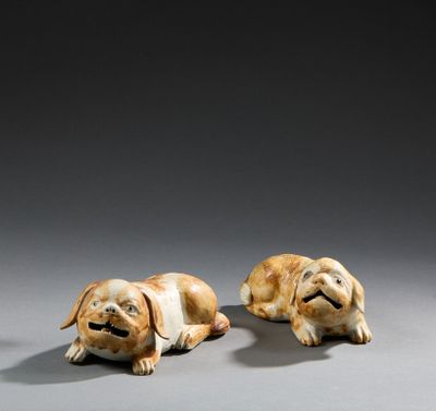 two small figurines of dogs laying down on a gray surface