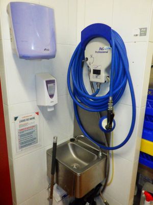 un tuyau bleu fixé au mur à côté d'un lavabo