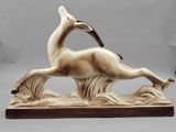 statue d'un cerf posé sur un rocher, avec un oiseau sur le dos
