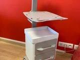a laptop on a cart in front of a red wall