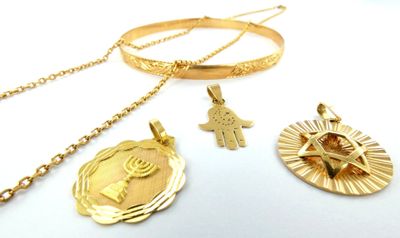 three gold necklaces with religious symbols on them on a white surface