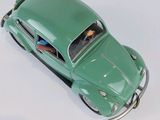 a green toy car that is sitting on a white surface