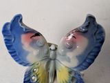 a small blue and yellow butterfly figurine on a white surface