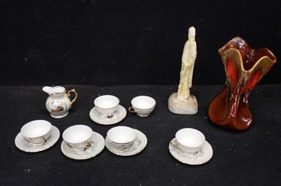 de nombreuses tasses et soucoupes, ainsi qu'un vase, posés sur la table