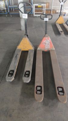 Plusieurs palettes sont alignées dans un entrepôt, avec une fourche d'un côté et une autre de l'autre.