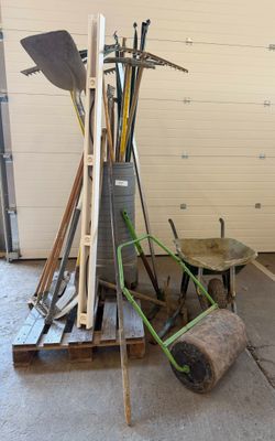 a pile of tools and a wheelbarrow in a garage