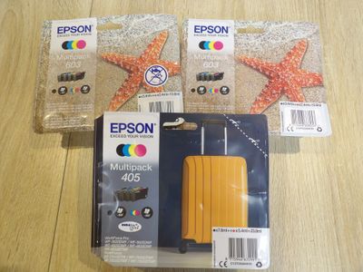 Trois cartouches d'encre Epson sont posées sur une table, à côté d'une étoile de mer