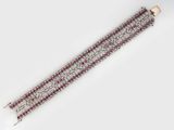 a close up of a red and white bracelet on a white surface