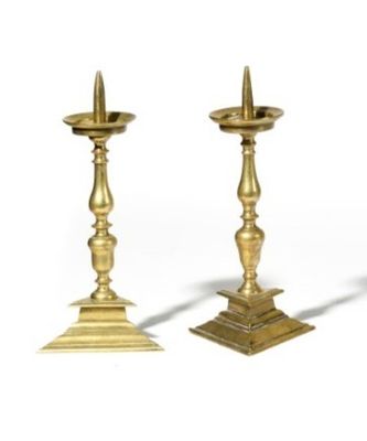 pair of antique brass candlesticks on pedestals on a white background