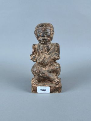 un gros plan sur une figurine représentant une personne assise sur un tabouret