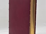 an open book with a red cover sitting on top of a white surface
