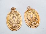 deux pendentifs en forme de médaille de saint Benoît plaqués or sur un fond blanc