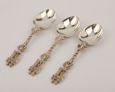 three silver spoons and a spoon with handles on a white surface