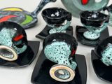 four black and green tea cups and saucers on the table