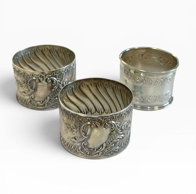 trois tasses en argent posées l'une à côté de l'autre sur une surface blanche