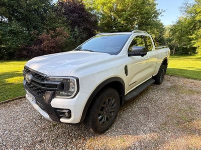 a white pickup truck parked in a gravel lot with trees in the background