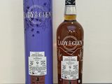 une bouteille de whisky « Lady of Glen » à côté d'une boîte violette