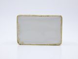 a small rectangular white and gold plate on a white surface