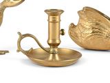 a gold plate with a bird on it next to a teapot and a candle holder