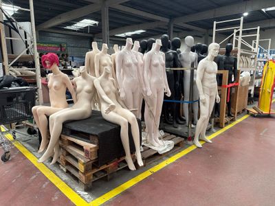 de nombreux mannequins assis sur une palette dans un entrepôt